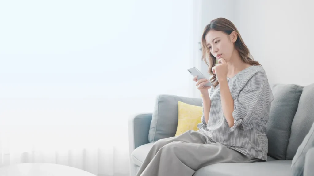 携帯を見て悩む女性