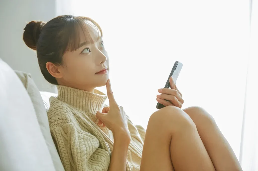 携帯を持ちながら考える女性