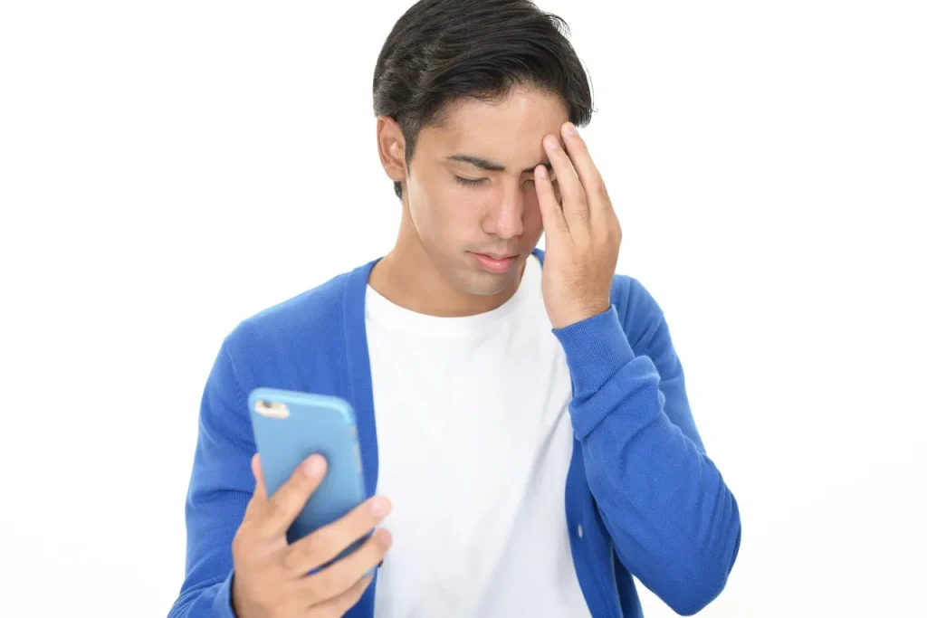 携帯を見て悩む男性