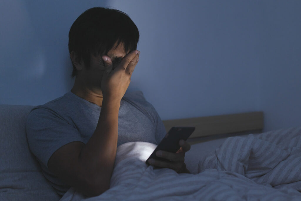 ベッドで目を押さえる男性